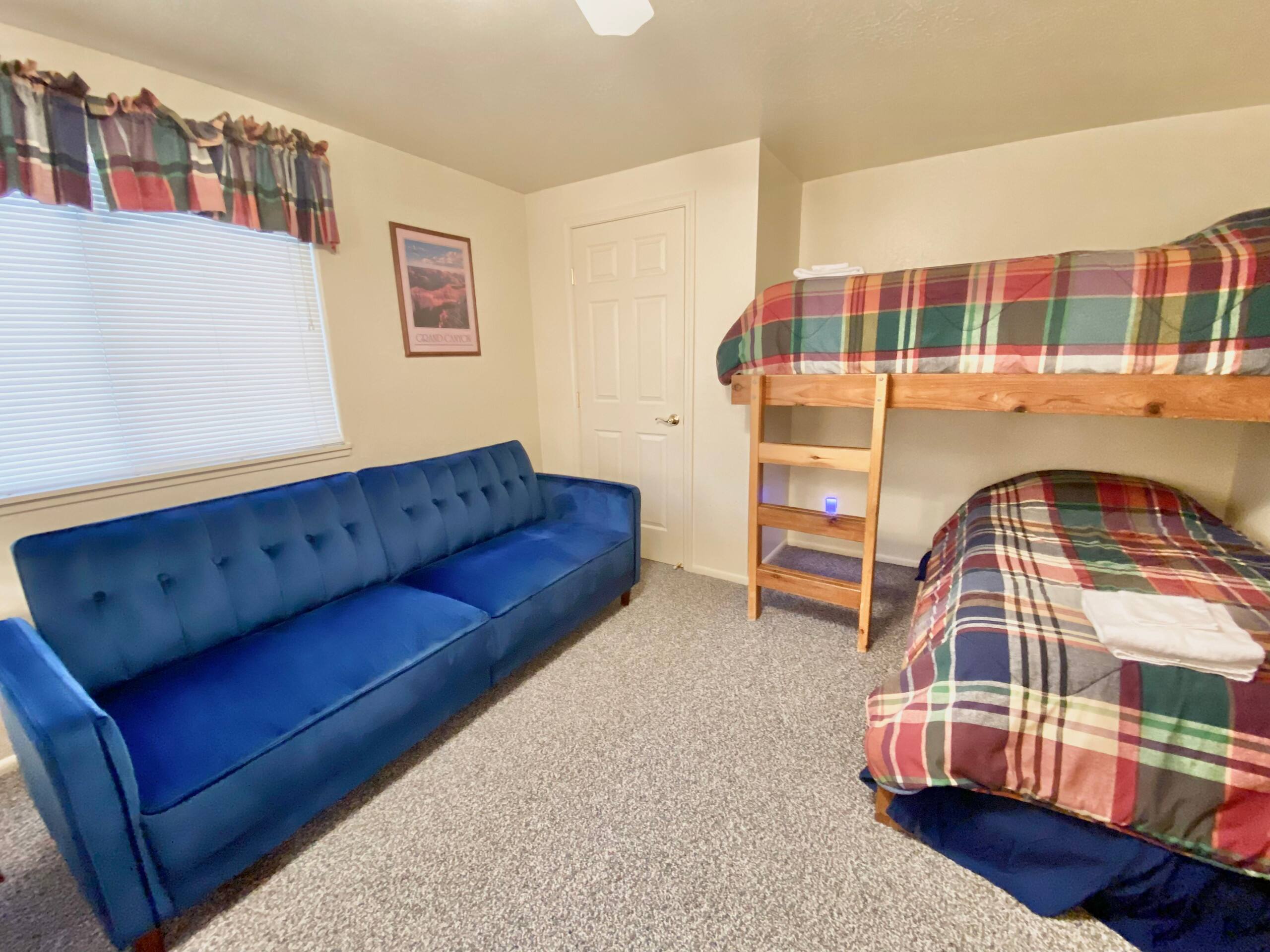 Upstairs Bedroom 3 with navy sofa and wood twin bunks in newer red and green plaid