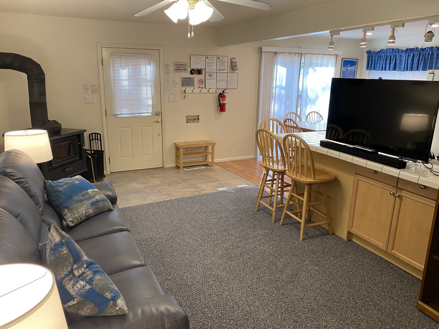 Open living room toward the breakfast bar, wood stove, and TV